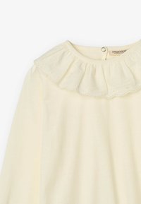 Top color crema con scollatura rotonda, collo arricciato e delicati bordi scallop, realizzato in morbido cotone.