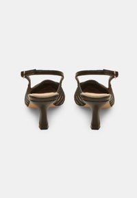 Escarpins slingback en cuir noir avec un talon incurvé et une tige texturée. Bride de cheville ajustable avec une boucle métallique.