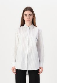 White long-sleeve button-up shirt with navy vertical stripes, featuring a chest pocket and a classic collar. Lightweight, semi-sheer fabric.