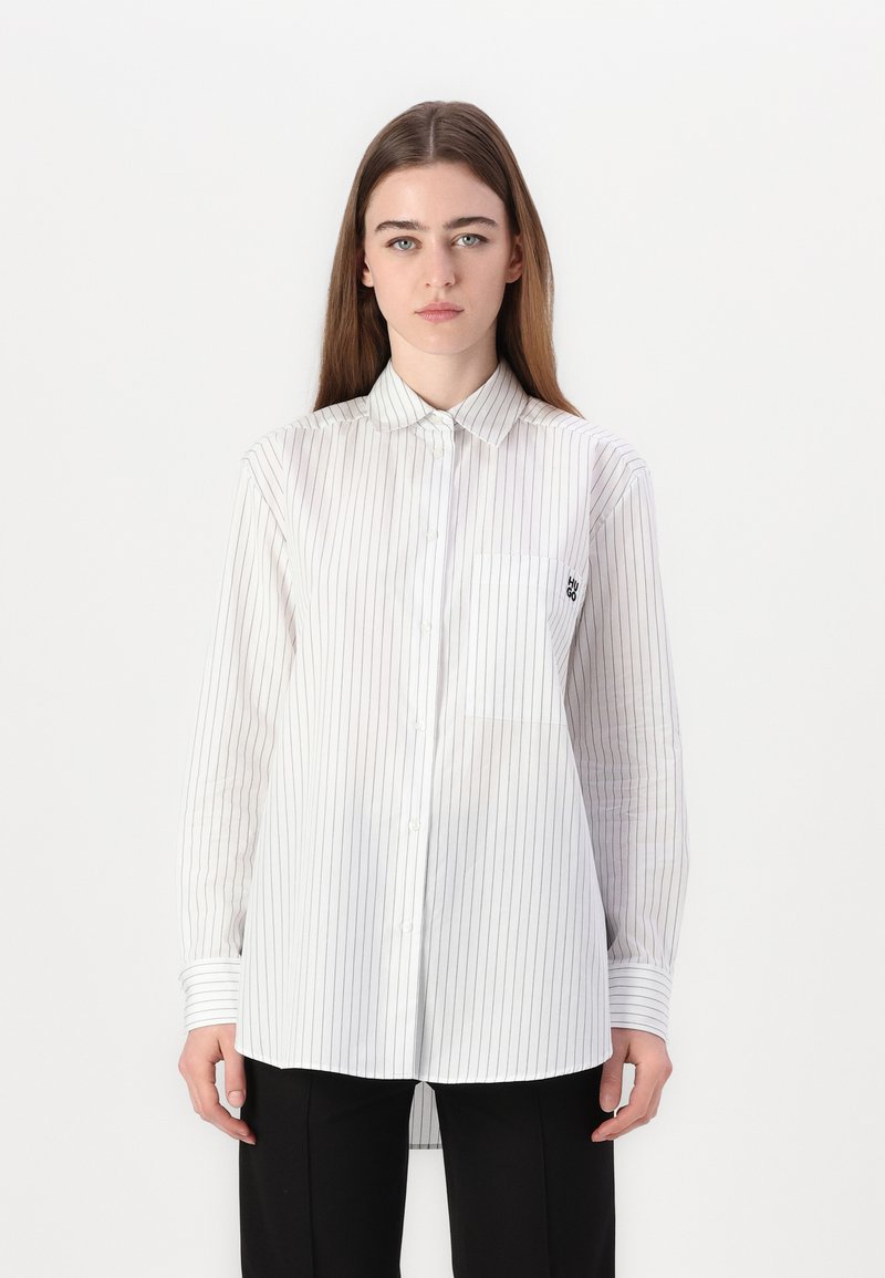 White long-sleeve button-up shirt with navy vertical stripes, featuring a chest pocket and a classic collar. Lightweight, semi-sheer fabric.
