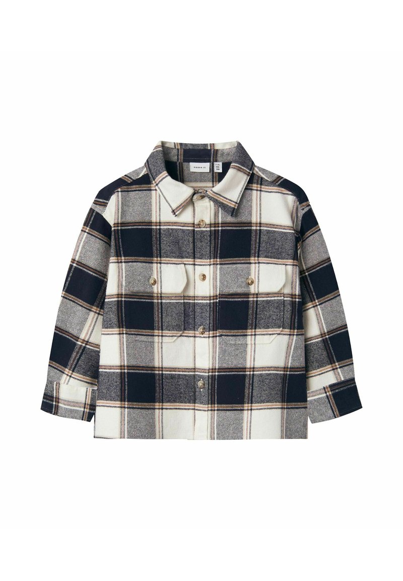 Flannel shirt featuring a navy and cream plaid pattern, button-up front, and two chest pockets with gold buttons. Long sleeves.