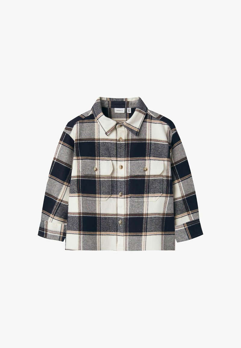 Flannel shirt featuring a navy and cream plaid pattern, button-up front, and two chest pockets with gold buttons. Long sleeves.