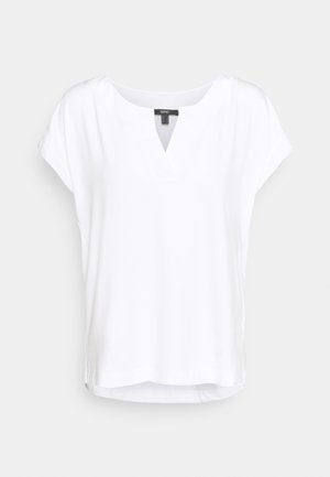 Biała bluzka z krótkim rękawem, z rozcięciem w kształcie litery V przy dekolcie, o luźnym, swobodnym kroju, prezentowana na jednolitym jasnym tle.