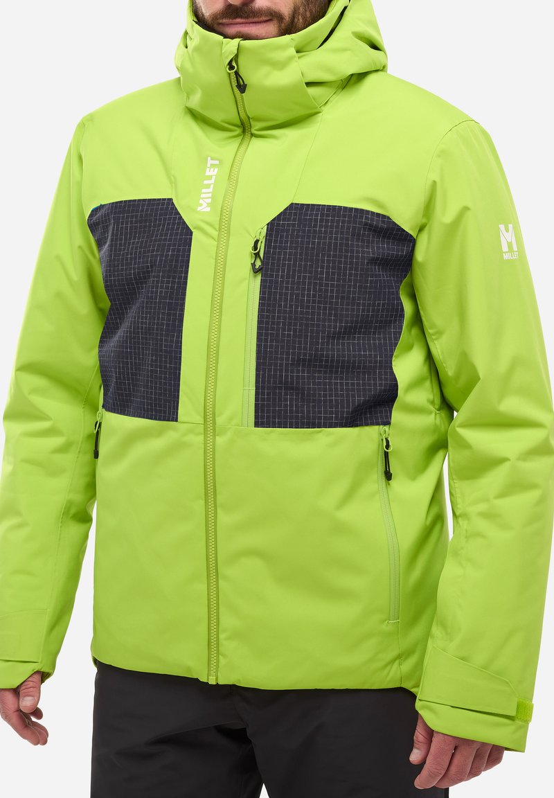 Veste isolée verte lime avec des panneaux à carreaux noirs. Présente un col haut, des poches zippées et des poignets ajustables.