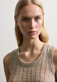 Top de tirantes tejido color beige con un patrón texturizado, que presenta un escote redondo acanalado y tirantes anchos, fabricado en un material ligero.