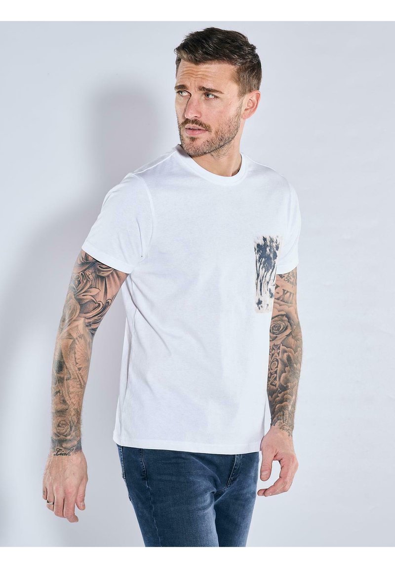 White cotton t-shirt with a round neckline and short sleeves. Features a textured pocket on the left with a dark, patterned accent.