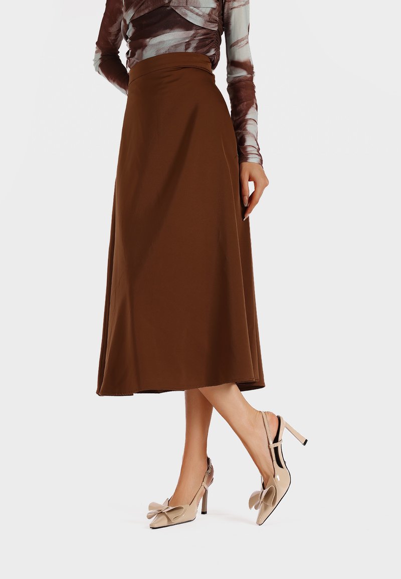 Gonna midi marrone con un design fluido, abbinata a décolleté beige con un accento a fiocco e tacco alto. Tessuto liscio.