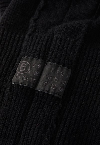 Guanti neri lavorati a maglia con texture a coste, dotati di un'etichetta con numeri da 0 a 23 che indicano le taglie, nella zona del polsino.