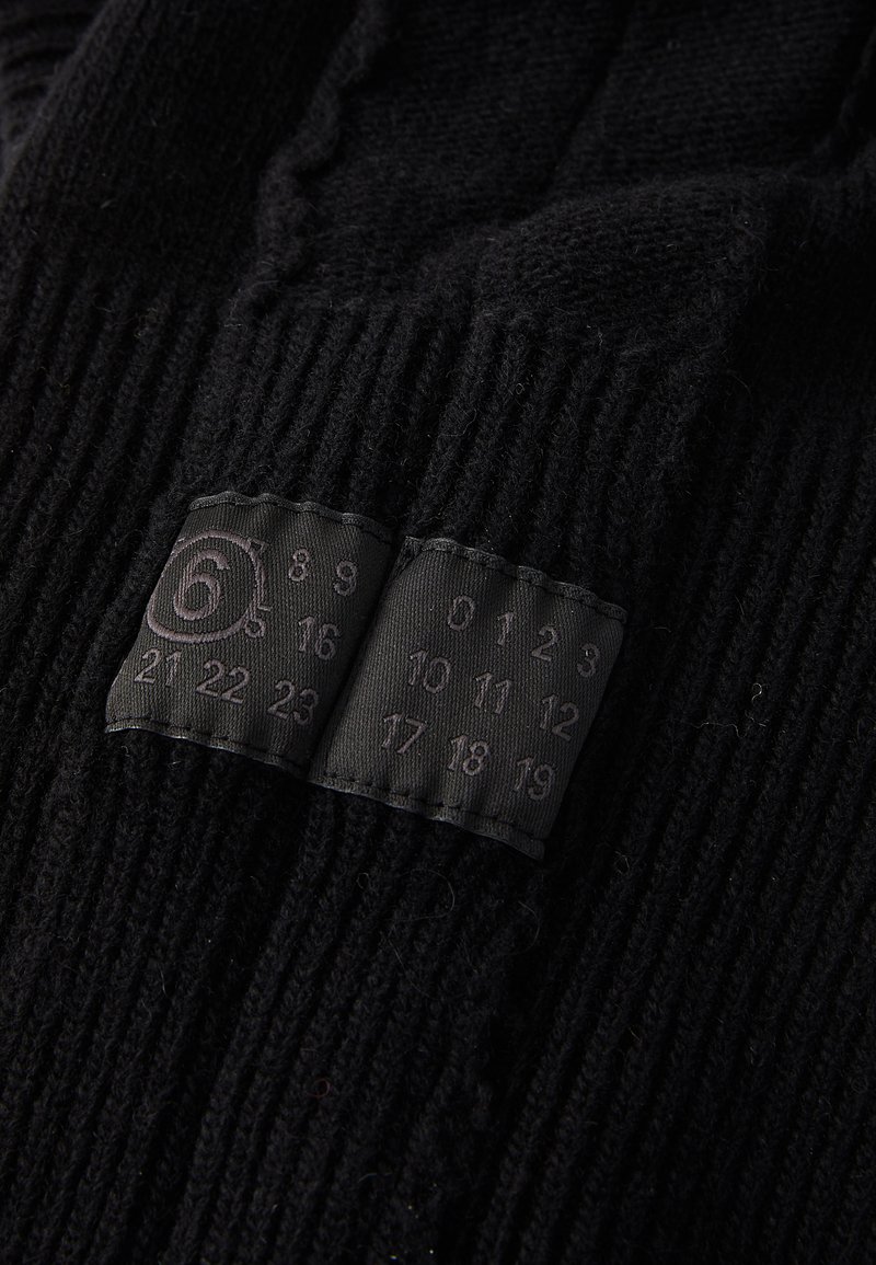 Zwarte gebreide handschoenen met ribbeltextuur, voorzien van een label met de nummers 0-23, die de maten aangeven, op het manchet.