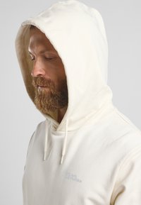 Helle Hoodies aus weichem Material, mit einer Kapuze mit Kordelzug und einem kleinen Logo auf der Brust. Glatte Textur und lässiges Design.