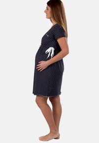 Abito premaman blu navy con pois bianchi, maniche corte, dettaglio con fiocco lateralmente e orlo scalloppato. Tessuto leggero.