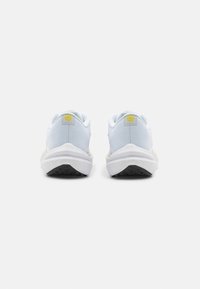 Zapatillas deportivas blancas con parte superior de malla, suela acolchada y suela exterior de goma negra. Presentan un acento de logo amarillo en el talón.
