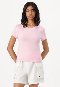 Rosa bomulls t-skjorte med kort erm, rund hals og en liten hvit Nike-logo på brystet. Brukt sammen med hvite shorts med sidelommer.