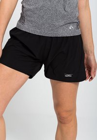 Pantalones cortos deportivos negros de corte holgado, hechos de tejido ligero. Presentan un logo en el dobladillo y paneles laterales texturizados para mayor transpirabilidad.