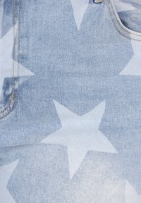 Tessuto di denim azzurro chiaro con un motivo di grandi stelle bianche; presenta cuciture visibili e un dettaglio tasca sul lato.