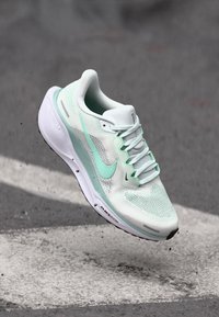 Licht mintgroen sportsschoen met een bovenwerk van mesh, veters en een witte zool; heeft een prominente swoosh-logo en textuuraccenten.