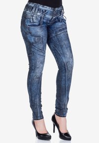 Helle blaue Skinny Jeans aus Denim mit mehreren Taschen, kontrastierenden Nähten und einem hohen Bund. Kombiniert mit schwarzen High Heels.