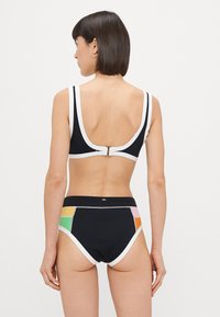 Black bikini top with white trim and back clasp; high-waisted bottoms featuring colorful accents in pink, green, and orange on sides.