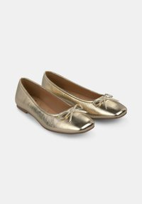 Bailarinas doradas con acabado metálico, punta redondeada y un lazo decorativo en cada zapato. Textura suave y suela plana.