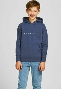 Hoodie blu navy con tasca a marsupio frontale, polsini elasticizzati e logo bianco "JACK&JONES" sul petto. Abbinato a jeans azzurri.