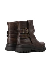 Stivaletti in pelle marrone con design morbido, doppie cinghie e fibbie, suole in gomma nera spessa e lieve elevazione del tacco.