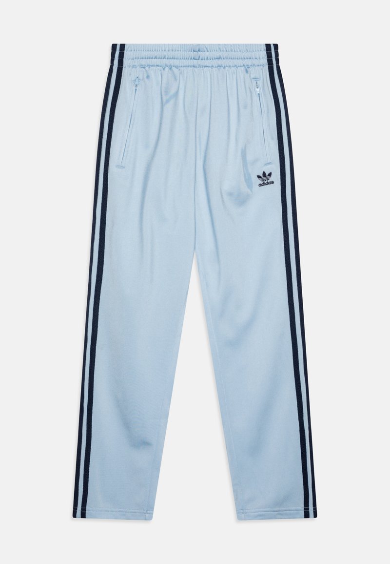 Šviesiai mėlynos sportinės kelnės su elastinga juosmeniu, šoninėmis užtrauktukų kišenėmis ir tamsiai mėlynomis juostelėmis šonuose. Su juodu Adidas logo.