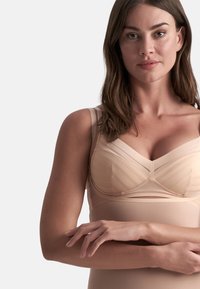 Reggiseno color nude con design a pannelli testurizzati e spalline larghe. Materiale morbido e elastico che si adatta alla forma del corpo, offrendo supporto.