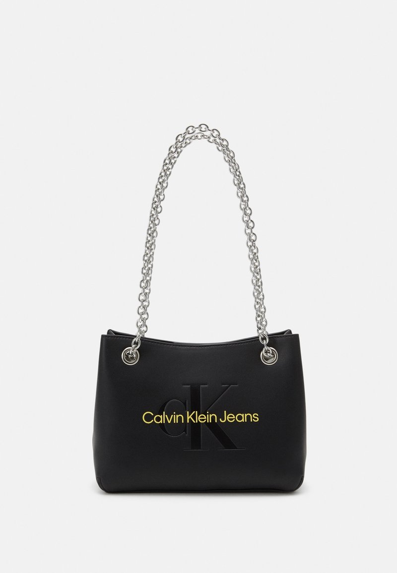 Borsa nera in ecopelle, con tracolla a catena argentata, logo in rilievo e testo giallo con la scritta "Calvin Klein Jeans".