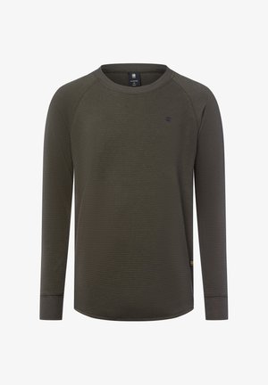Langärmeliges kreisförmiges Shirt in dunkelolivgrünem Waffelstrick mit kleinem Logo auf der Brust und gerippten Bündchen, auf weißem Hintergrund dargestellt.
