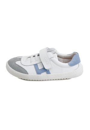 Zapatilla blanca con puntera de ante gris, tacón y detalles laterales en azul, tira de Velcro y suela blanca texturizada sobre un fondo blanco liso.