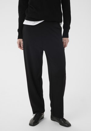 Black trousers made of soft fabric, featuring a relaxed fit, straight legs, and a smooth texture, paired with black lace-up shoes.