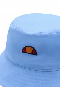 Błękitny kapelusz z szerokim rondem, wykonany z materiału, z haftowanym logo w pomarańczowo-czerwonym półkolistym wzorze. Gładka faktura, okrągły kształt.