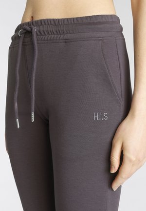 Lila Jogginghosen aus weichem Material, ausgestattet mit einem elastischen Bund und Kordelzug sowie seitlichen Taschen. "H.I.S" ist auf der Vorderseite gestickt.