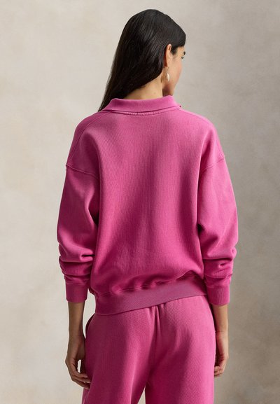 Ροζ βαμβακερό φούτερ με άνετη εφαρμογή, ριμπ μανσέτες και ζώνη μέσης. Διαθέτει κλασικό γιακά και υφή ύφασματος.