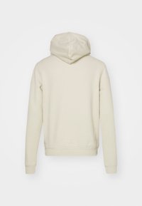 Kermanvärinen huppari, jossa on pehmeä pinta, säädettävä kiristysnauhallinen huppu, pitkät hihat sekä resorit hihansuissa ja helmassa. Vain takakatselukuva.