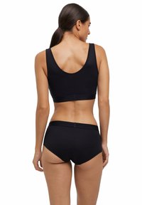 Zwarte sportbeha en bijpassende boyshorts van gladde stof, met een scoop rug, brede banden en een naadloos ontwerp.