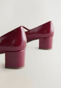 Burgundy lakattu nahka lohko-korkoiset kengät tekstuuripinnalla, joissa on terävä kärki ja nilkkaremmi tuen tarjoamiseksi.