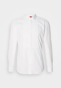 Chemise blanche à manches longues en coton, dotée d'un plastron avant avec des plis verticaux. Col classique et poignets à boutons. Texture lisse.