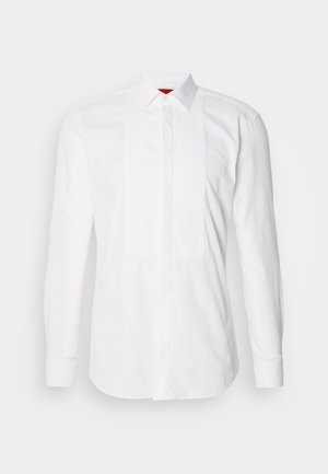 Chemise blanche à manches longues en coton, dotée d'un plastron avant avec des plis verticaux. Col classique et poignets à boutons. Texture lisse.