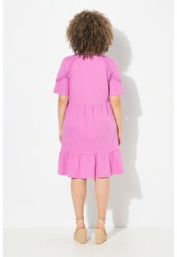 Vestido rosa de manga corta con dobladillo acampanado, que presenta cintura fruncida y detalle texturizado en los hombros. Combinado con sandalias de cuña.
