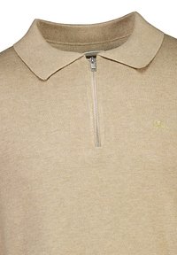 Beige tröja med dragkedja vid kragen, tillverkad av ribbat tyg. Har en broderad logotyp på vänster sida. Slät textur.