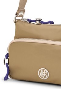 Borsa a tracolla in tessuto beige con hardware argentato, due sezioni con zip, dettagli in corda viola e un logo circolare sulla parte anteriore.
