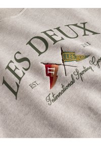 Felpa grigia in cotone con ricami verdi e arancioni, testo "LES DEUX," anno di fondazione e design di bandiere.