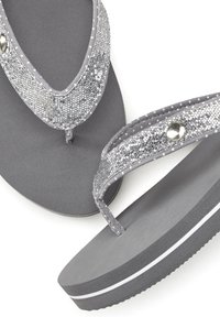 Gray flip-flops with a textured gray sole and glittery silver straps. The straps feature circular silver accents near the toe post.
