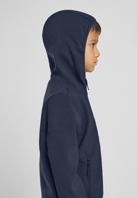 Navy blue hooded jacket made of smooth, lightweight material. Features a zippered pocket and a fitted hood designed for comfort.