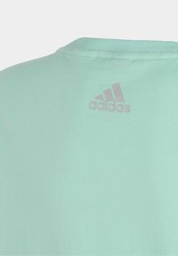Mátově zelené bavlněné tričko s kulatým výstřihem, s jemným šedým logem Adidas na zadní straně blízko výstřihu. Hladká textura.