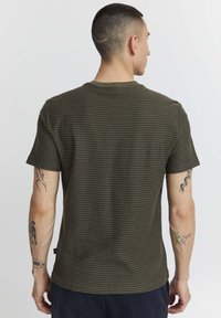 Camiseta de manga corta a rayas en verde oliva con cuello redondo. Tejido suave y texturizado que presenta finas rayas horizontales y un ajuste estándar.