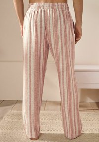 Pantalons de lounge légers à rayures rouges et blanches, avec une taille élastique et des poches latérales, offrant une coupe décontractée et une texture douce.