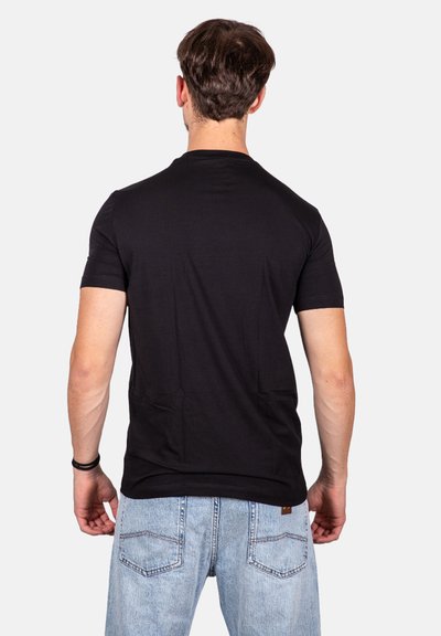 T-shirt nera a maniche corte realizzata in tessuto morbido, taglio aderente, con scollatura a girocollo. Indossata con jeans azzurri chiari con tasche posteriori.