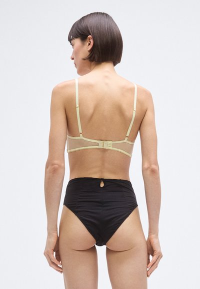 Braguita de bikini negra de talle alto con un pequeño detalle de ojal en la parte trasera, combinada con un sujetador tipo bralette de tirantes verdes claros con tirantes ajustables y cierre de gancho.